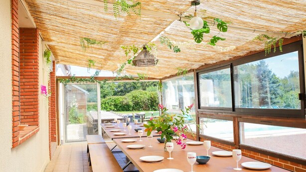 A dining area with a long table set for a meal, large windows, and a thatched ceiling. - So Villa Le Tertre (41) - Heated pool - Nordic bath - 1h35 Paris - 44 p. (Le Poislay)