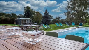 A poolside area with a wooden table, lounge chairs, and a pool. - So Villa Le Tertre (41) - Heated pool - Nordic bath - 1h35 Paris - 44 p. (Le Poislay)