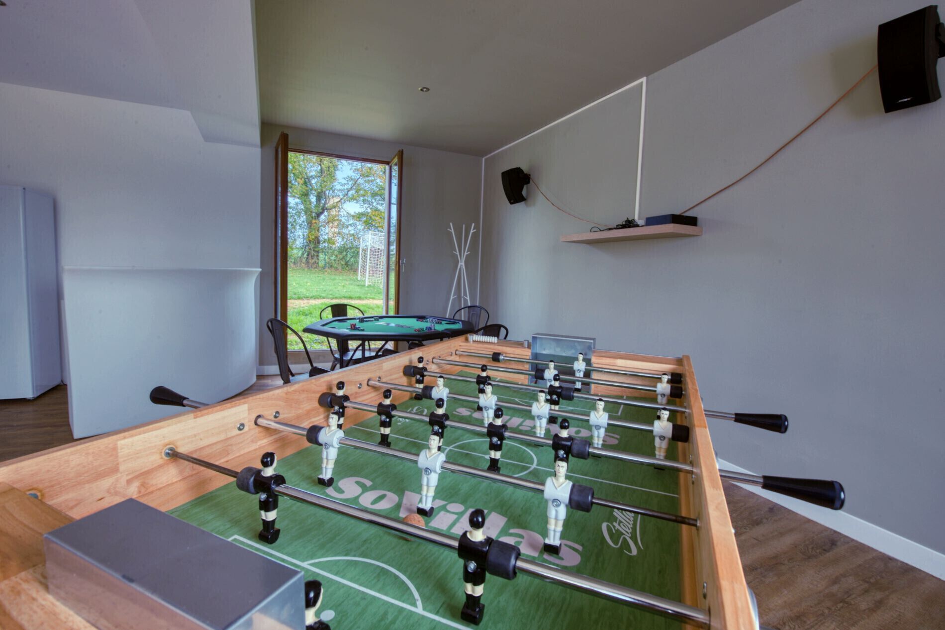 Ett fotbollsspelbord i ett rum med utsikt över en gräsyta genom ett fönster.