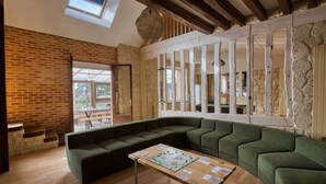 A modern living room with a green sectional sofa, a wooden coffee table, and a stone wall. - So Villa Le Tertre (41) - Heated pool - Nordic bath - 1h35 Paris - 44 p. (Le Poislay)