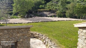 A stone pathway leading to a grassy area with a view of a mountainous landscape. - ABRIGO DO CABECINHO (Cortes do Meio)