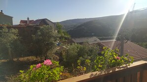 A residential area with houses, a garden, and a view of hills. - ABRIGO DO CABECINHO (Cortes do Meio)