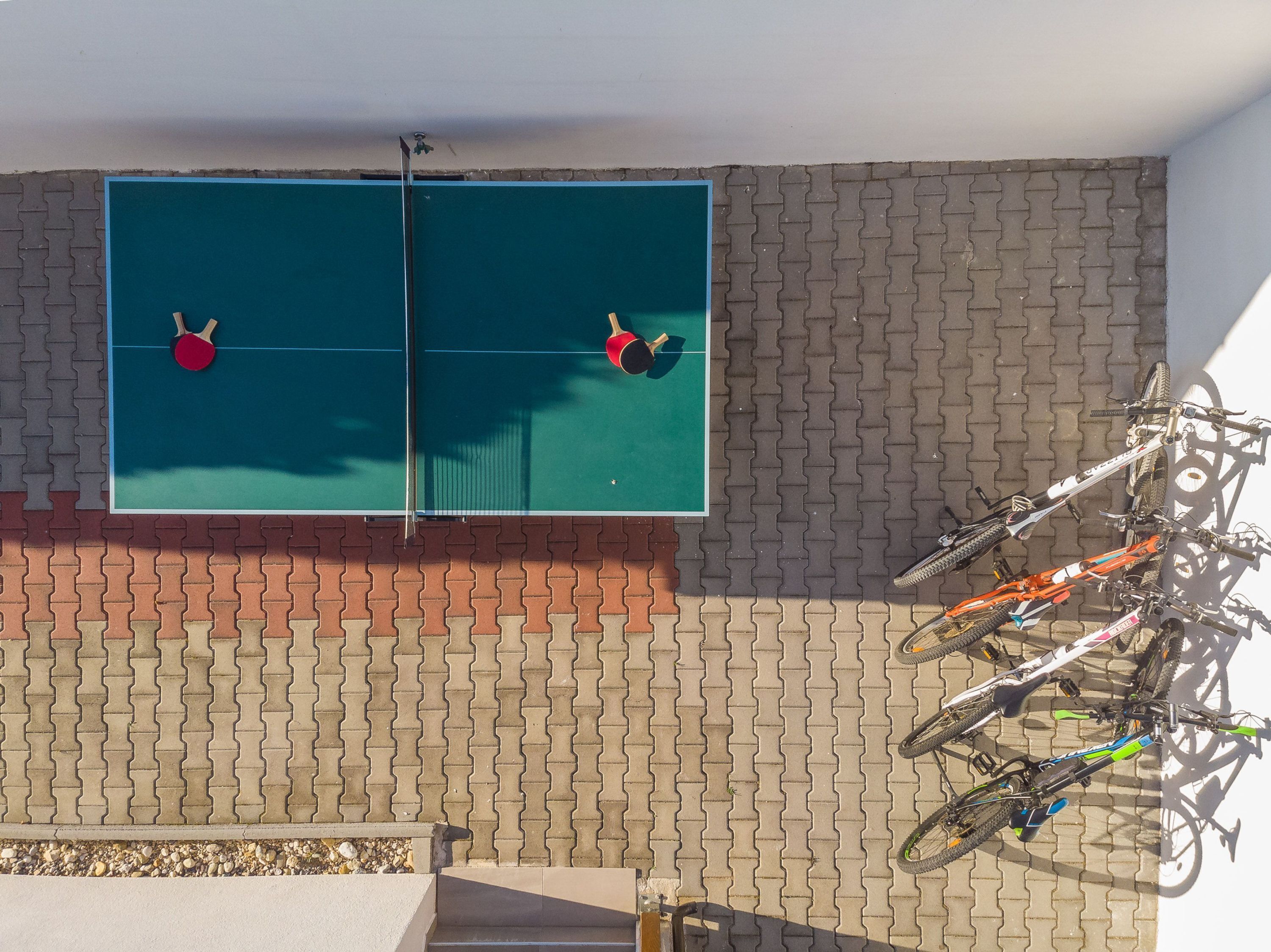 Ein Tischtennis-Tisch, ein Fahrradständer und eine Ziegelwand.