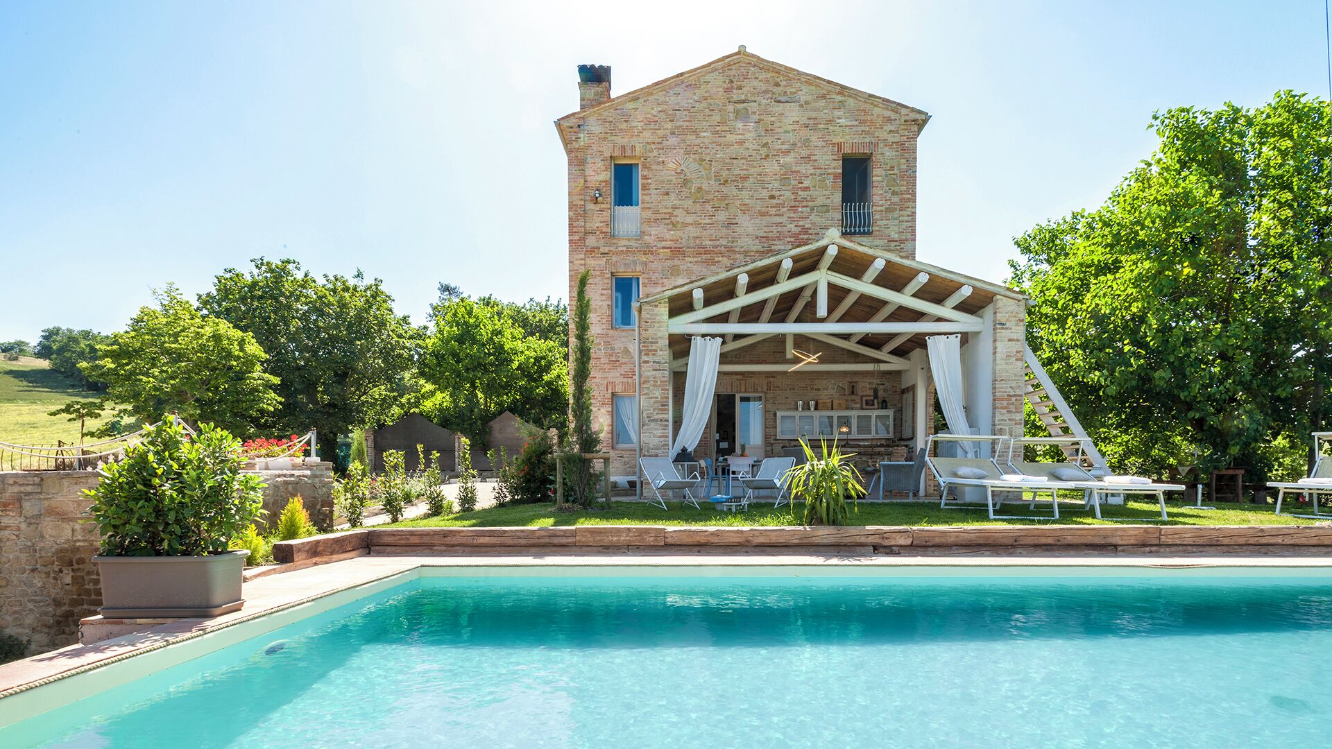 A stone building with a pool and outdoor seating.