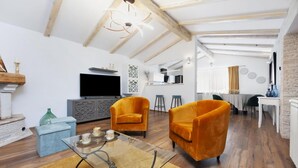 A modern living room with a glass coffee table, two orange armchairs, a flat-screen TV, and a fireplace. - Villa Dioniz Zadarvillas (Rovinj)