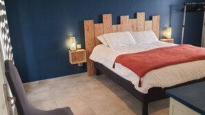 A neatly made bed with a wooden headboard, two bedside lamps, and a red throw blanket.