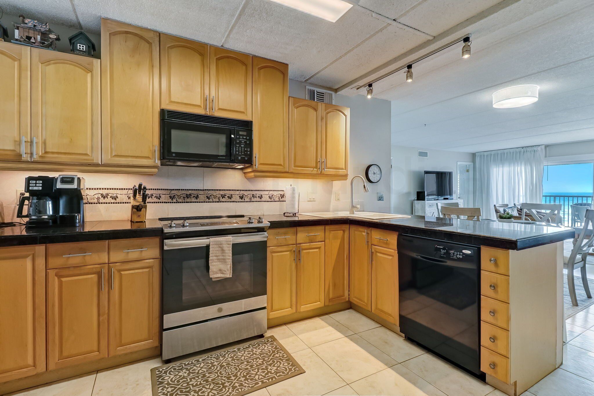 A modern kitchen with wooden cabinets, stainless steel appliances, and a large island with a dishwasher.