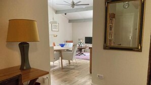 Una habitación con una mesa de comedor, sillas, una lámpara y un espejo en la pared.