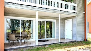 Un patio techado con una mesa y sillas, una puerta corrediza de vidrio y un pequeño porche.