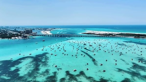 Vista aérea de una zona costera con un puente, aguas turquesas cristalinas y numerosos barcos.