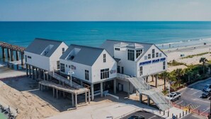 Un hôtel situé en bord de mer, composé de plusieurs bâtiments blancs, doté d’une jetée et offrant une vue sur la plage.
