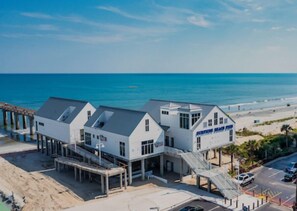 A beachfront hotel with multiple white buildings, a pier, and a beach view.