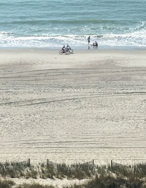 A beach with a bicycle and two people standing near the water.