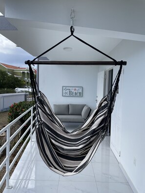 Ein Hängesessel, ein graues Sofa und ein Schild mit der Aufschrift 'Love the Beach'.
