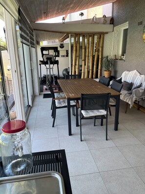 A dining area with a wooden table and chairs, a large window, and a view of the outside.