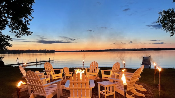 A lakeside seating area with wooden Adirondack chairs around a central fire pit. - Heros Hideaway, private 1acre flat grassy yard, majestic sunsets (South Hero)