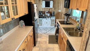 A kitchen with wooden cabinets, a granite countertop, a dishwasher, a sink, and a microwave. - Heros Hideaway, private 1acre flat grassy yard, majestic sunsets (South Hero)
