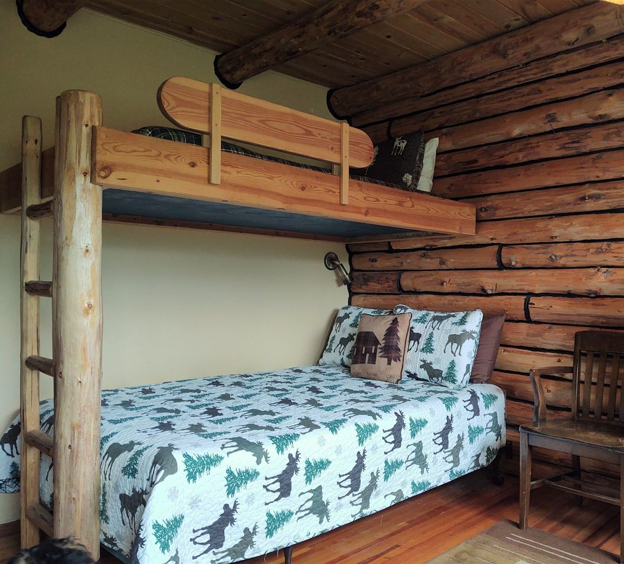Ein Blockhausszimmer mit einem Etagenbett, einer Holzkammer und einem Sessel.