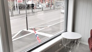 A room with two white round tables, a window with a view of a street, and a red chair. - Lofoten Overnatting - Leknes - Hostel (Vestvågøy)