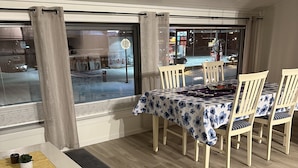 A dining area with a table set for four, wooden chairs, a white table, and a patterned tablecloth. - Lofoten Overnatting - Leknes - Hostel (Vestvågøy)