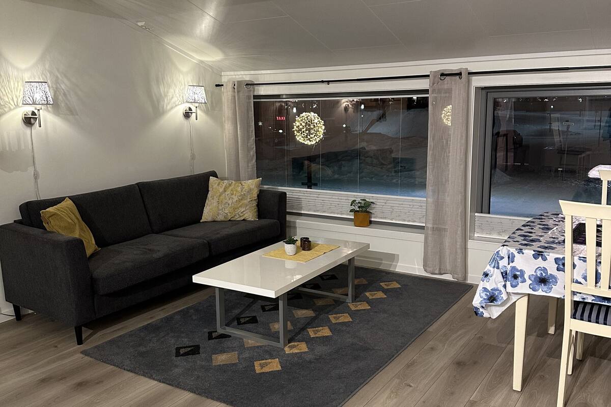 A modern living room with a sofa, coffee table, and a dining area with a table and chairs.