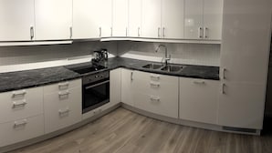 A modern kitchen with white cabinets, a black countertop, and a built-in oven. - Lofoten Overnatting - Leknes - Hostel (Vestvågøy)