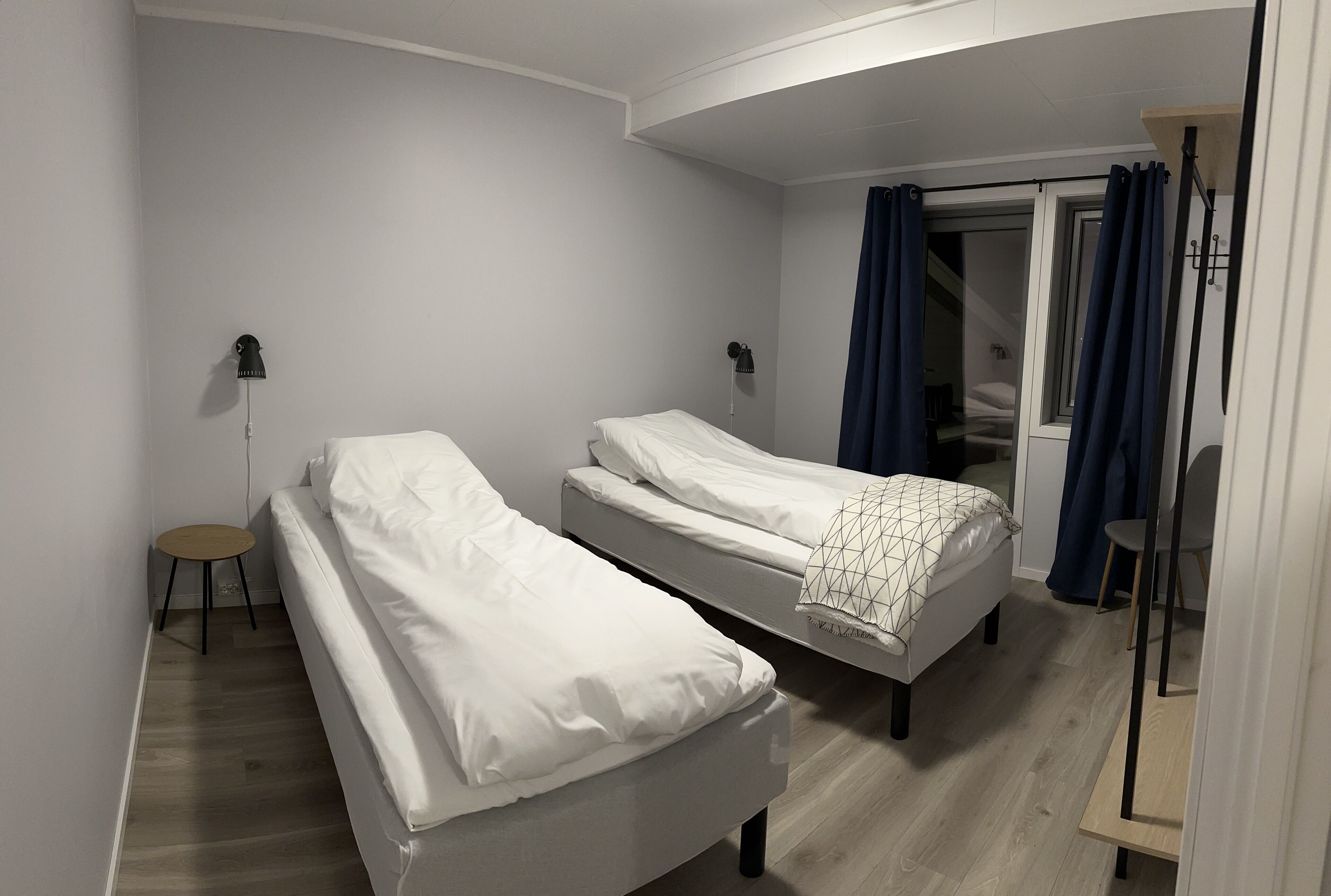 A bedroom with two single beds, a small round table, and a wardrobe.