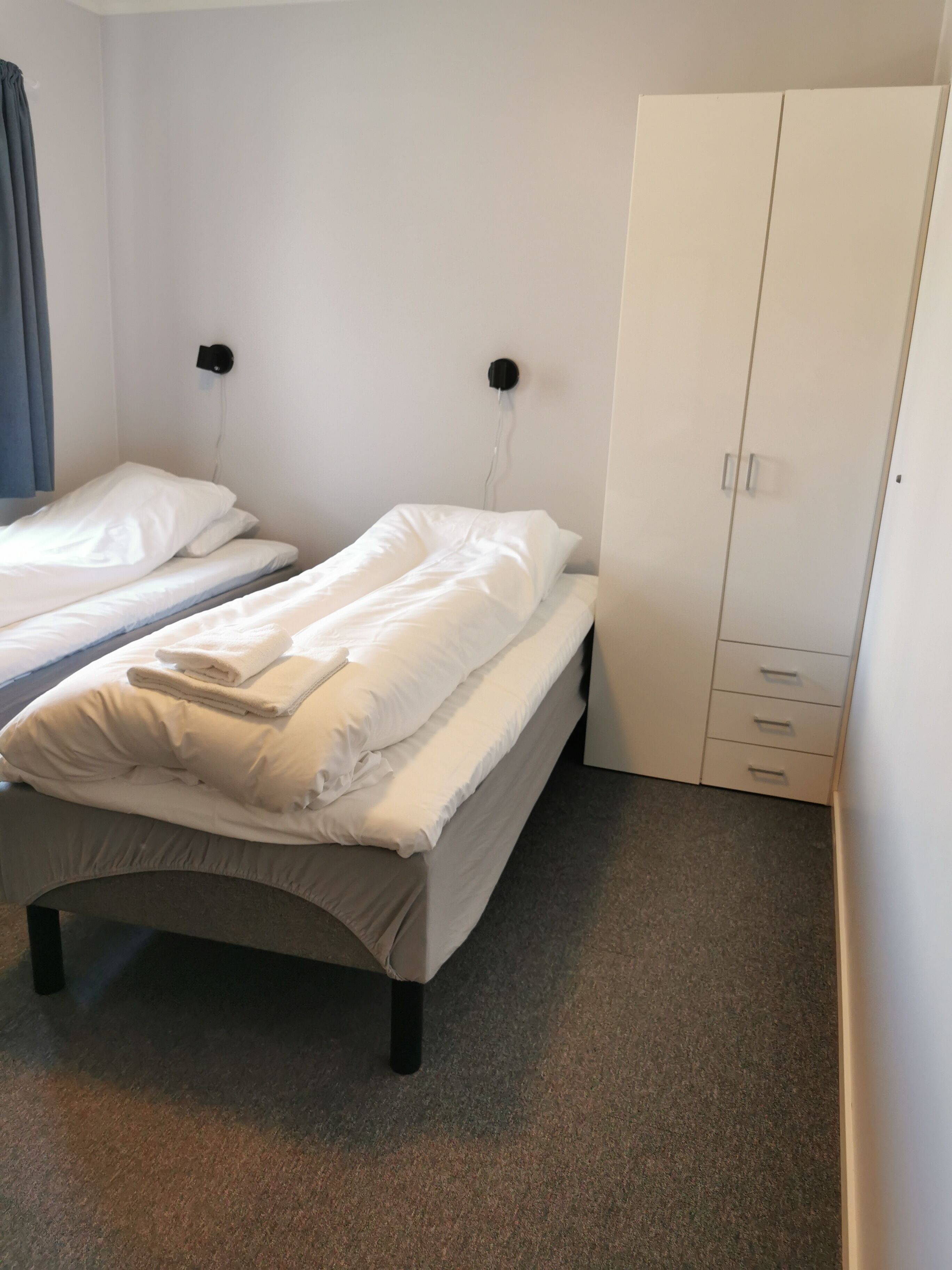 Ein Schlafzimmer mit zwei Einzelbetten, einem Kleiderschrank und Teppichboden.