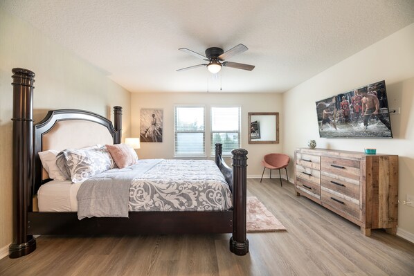 A bedroom with a four-poster bed, a wooden dresser, a ceiling fan, and a large window. - Waterpark, Lazy river! Disney pool home. (Davenport)
