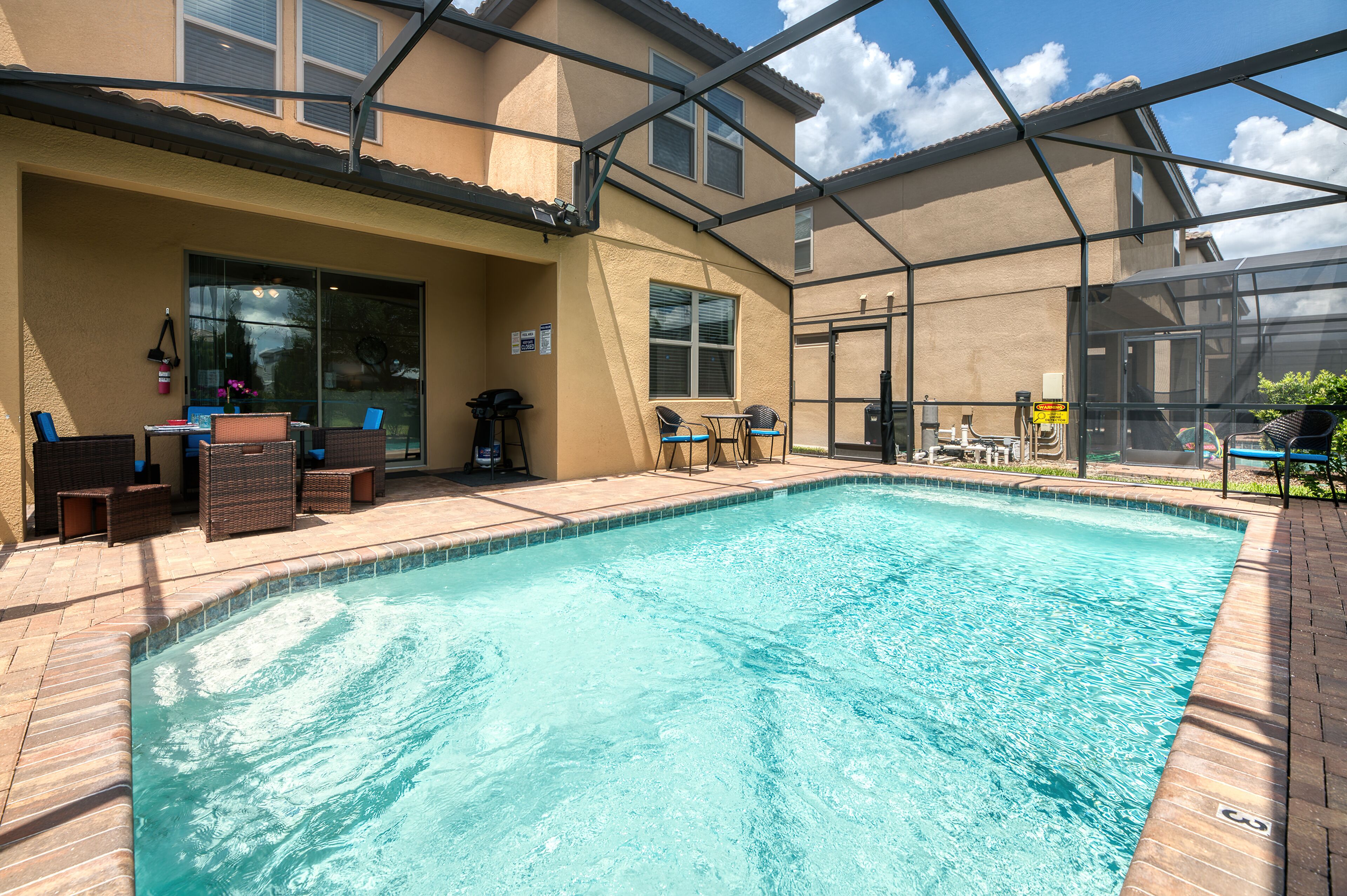 Une piscine avec un patio couvert, un espace salon extérieur et une vue sur la maison.