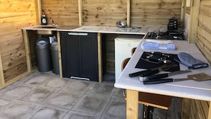 Cozinha compacta com paredes de madeira, pia, lava-louças, fogão e diversos utensílios de cozinha.