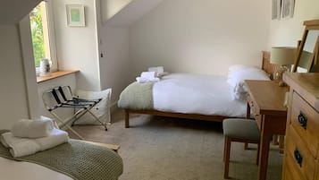 A bedroom with two beds, a wooden dresser, a chair, and a small table.