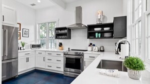 Une cuisine moderne avec des meubles blancs, des appareils en acier inoxydable et un sol bleu.
