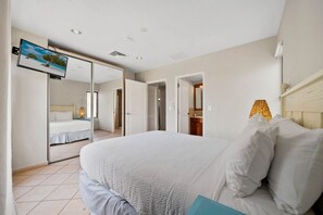 Een slaapkamer met een bed, een televisie en een spiegel.