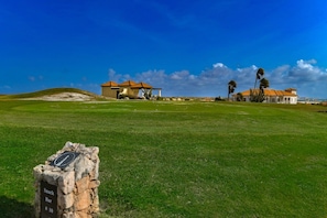 Un campo de golf con un club de campo, un bar de aperitivos y un cielo azul despejado.