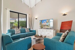A living room with teal sofas, a coffee table, and artwork on the walls.