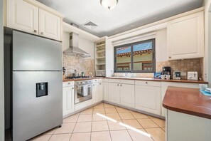 Una cocina moderna con armarios blancos, electrodomésticos de acero inoxidable y un ventanal con vistas.