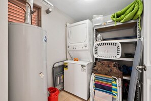 A compact laundry room with a washing machine, dryer, and a drying rack.