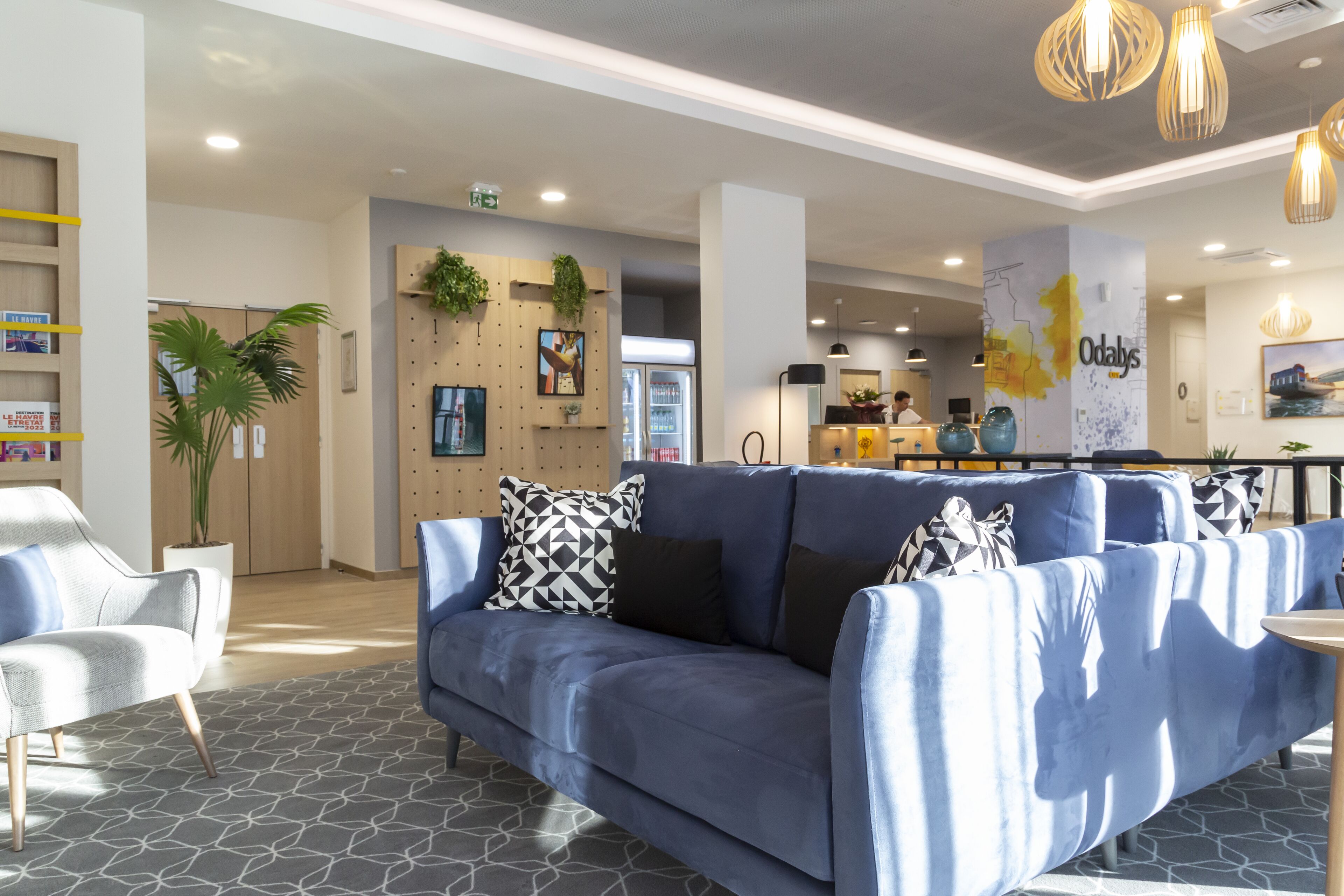 A modern lobby with a blue sofa, a white armchair, and a patterned rug.