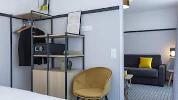 Una habitación de hotel con cama, escritorio con silla, sofá y una mesita de noche con lámpara.