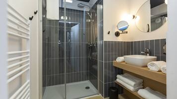 Ein modernes Badezimmer mit einer Duschkabine, einem weißen Waschbecken und einem Spiegel.