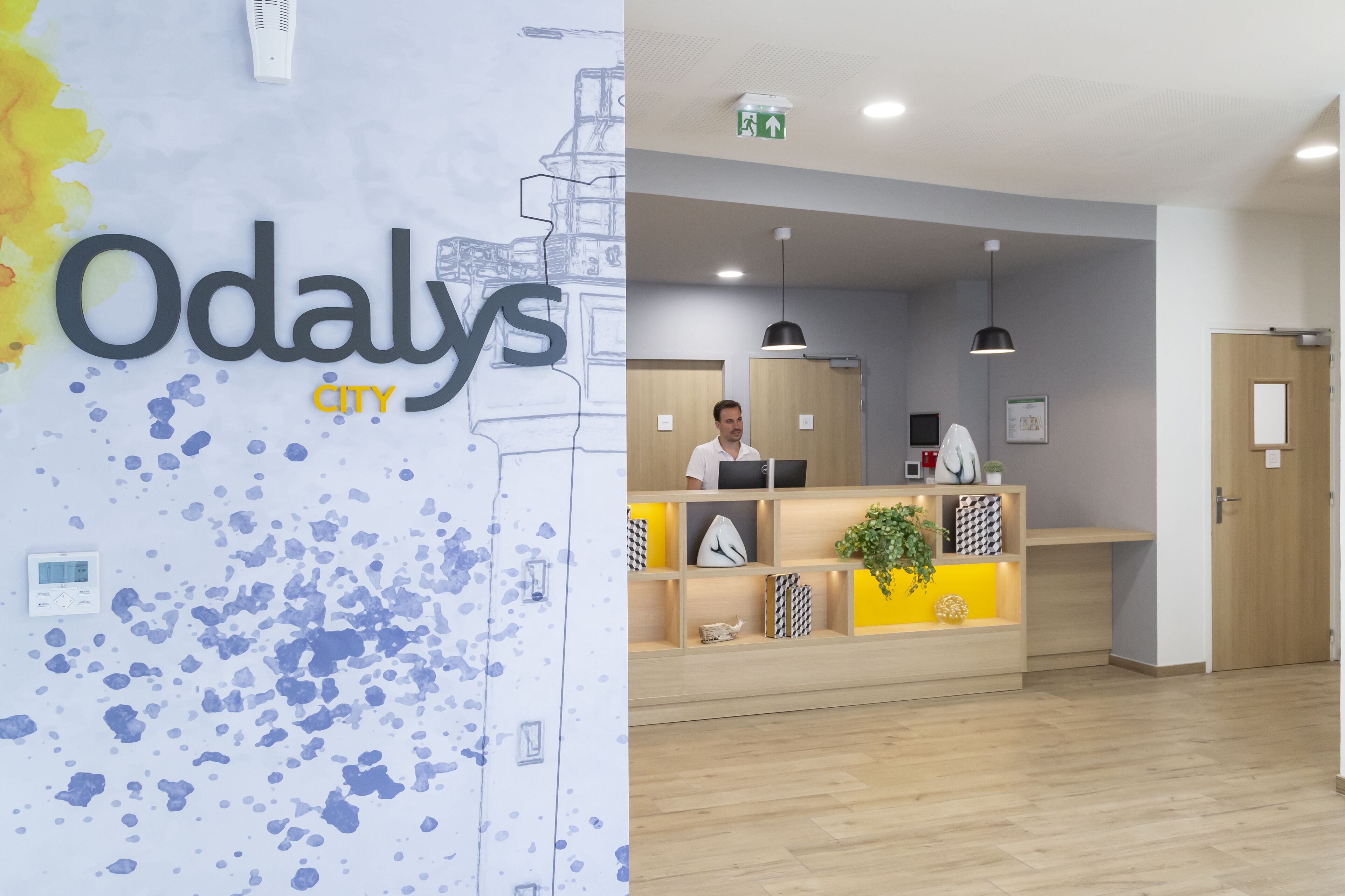 A reception desk with a modern design, a digital display, and a plant.