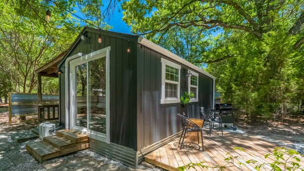 A small wooden cabin with a porch, large windows, and a grill outside. - Chic PRIVATE cabin in the woods --> queen bed, deck, high-speed Wifi (Greenville)