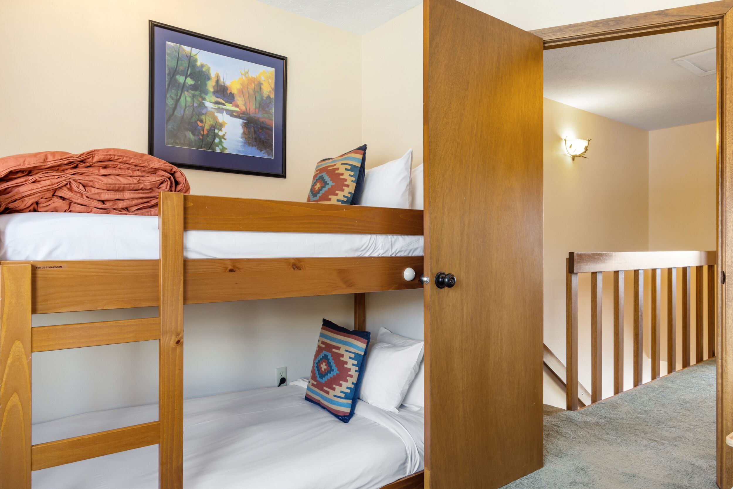 A bunk bed room with a door leading to a staircase.