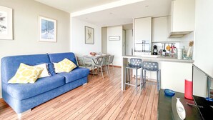 A modern living room with a blue sofa, wooden flooring, and a dining area with a table and chairs. - Oceanfront studio with swimming pool in La Chaume (Les Sables-d´Olonne)
