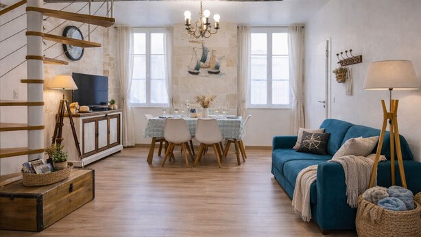 Een gezellige woonkamer met een eethoek, houten vloeren, een blauwe bank en een kroonluchter.