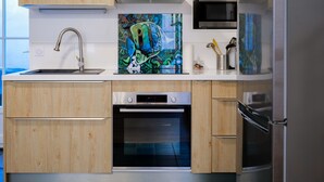 Een moderne keuken met houten kastjes, een roestvrijstalen spoelbak, een oven, een magnetron en een koelkast.