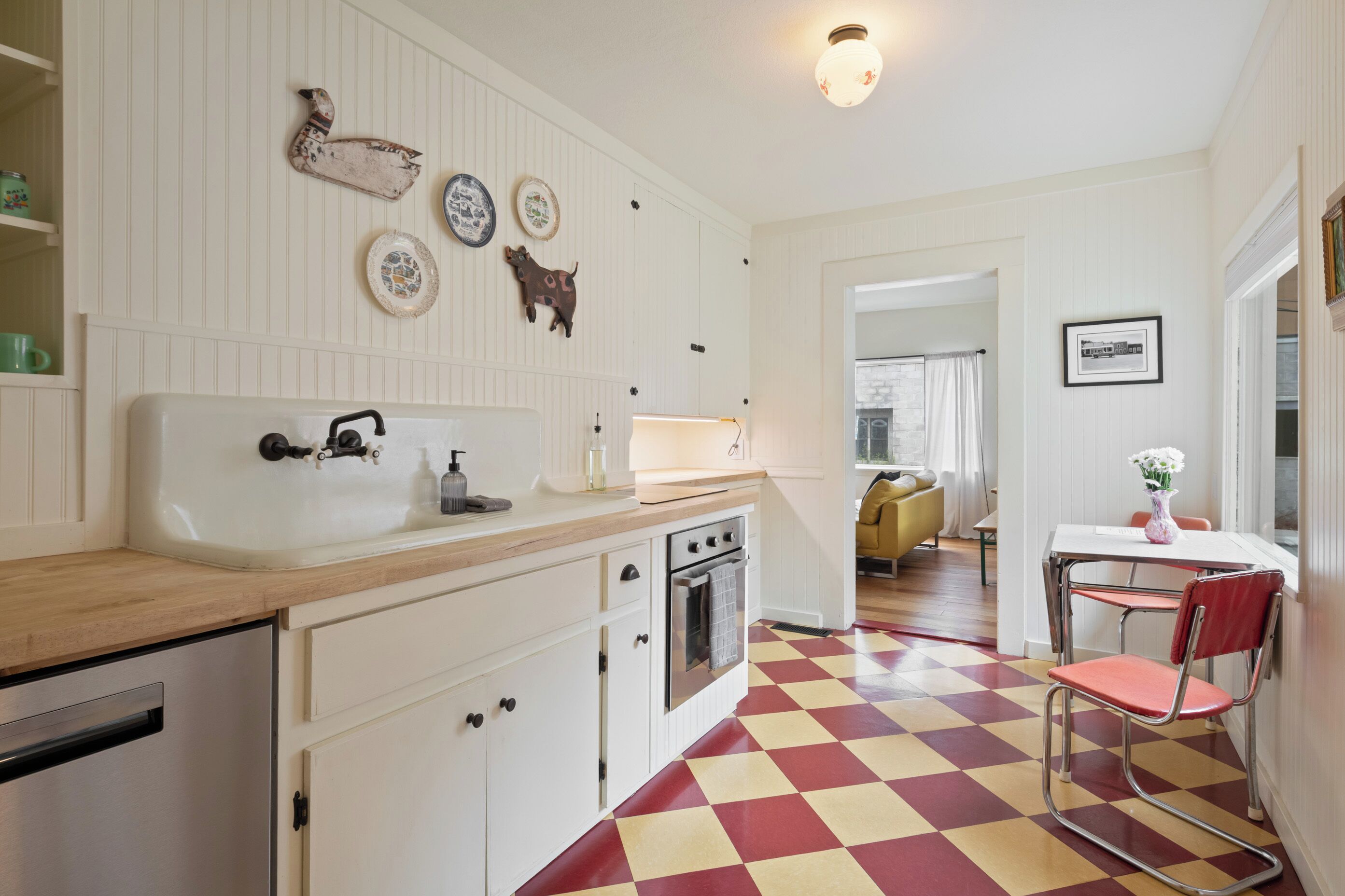 A kitchen with a checkered floor, a sink, cabinets, and a stove.