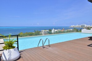 A wooden deck with a pool overlooking a beach and city skyline. - Fanthakstico Apart Vista al Mar Cancun (Cancun)