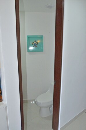 A bathroom with a white toilet, a blue-framed mirror, and a wooden door frame. - Fanthakstico Apart Vista al Mar Cancun (Cancun)